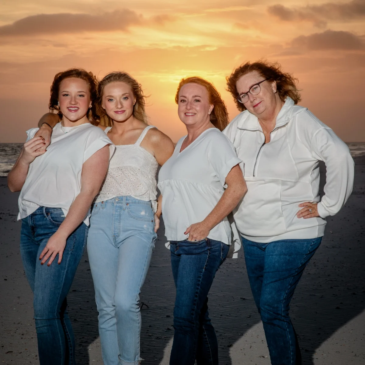 Four girls standing on the beach during a sunset photo session in Fort Morgan, Alabama shot by a professional photographer.