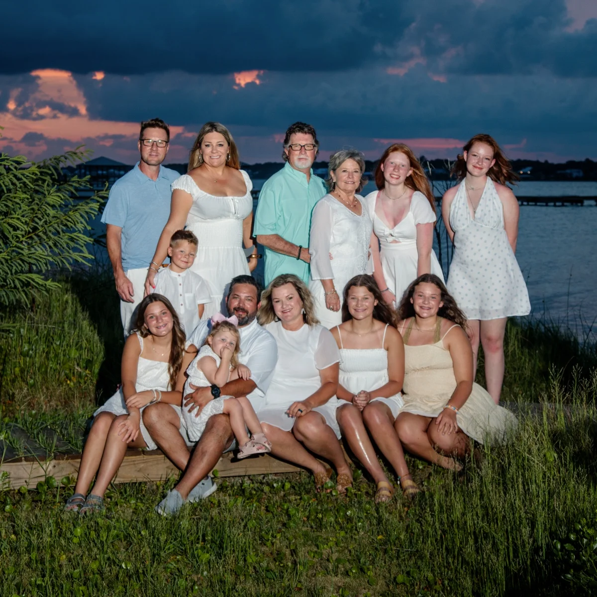 A family of 13 having their sunset family peach portraits done on the beach in Fort Morgan, Alabama.