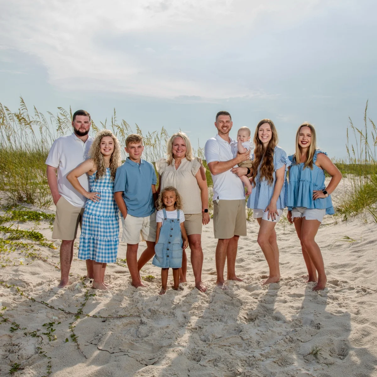 Family portraits of a family of nine standing on the white sand by the sea oats having their photos taken in Fort Morgan Alabama
