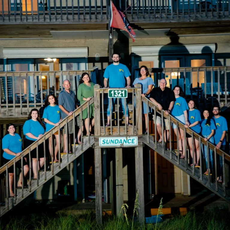 A family photo session at a beach house of a large family posed on the steps of their beach house.