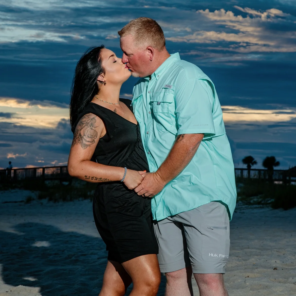 A man and woman kissing at sunset during a beach photo session in Fort Morgan, Alabama.