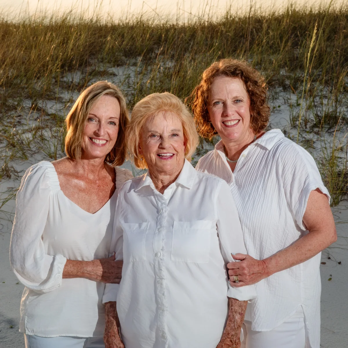 Three women smiling happy on the beach during their photo session in Fort Morgan, Alabama.