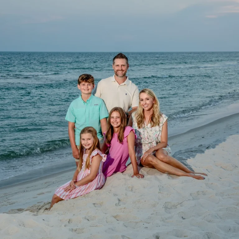 A family of five posed by the water's edge for a professional photographer portrait set in Fort Morgan, Alabama.
