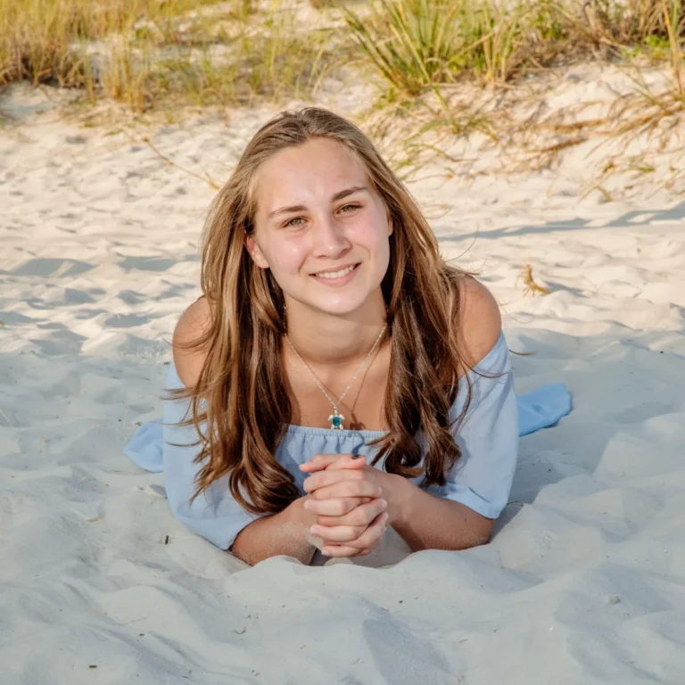 A photo of a high school senior sitting on the beach in the sand in Port Morgan, Alabama.