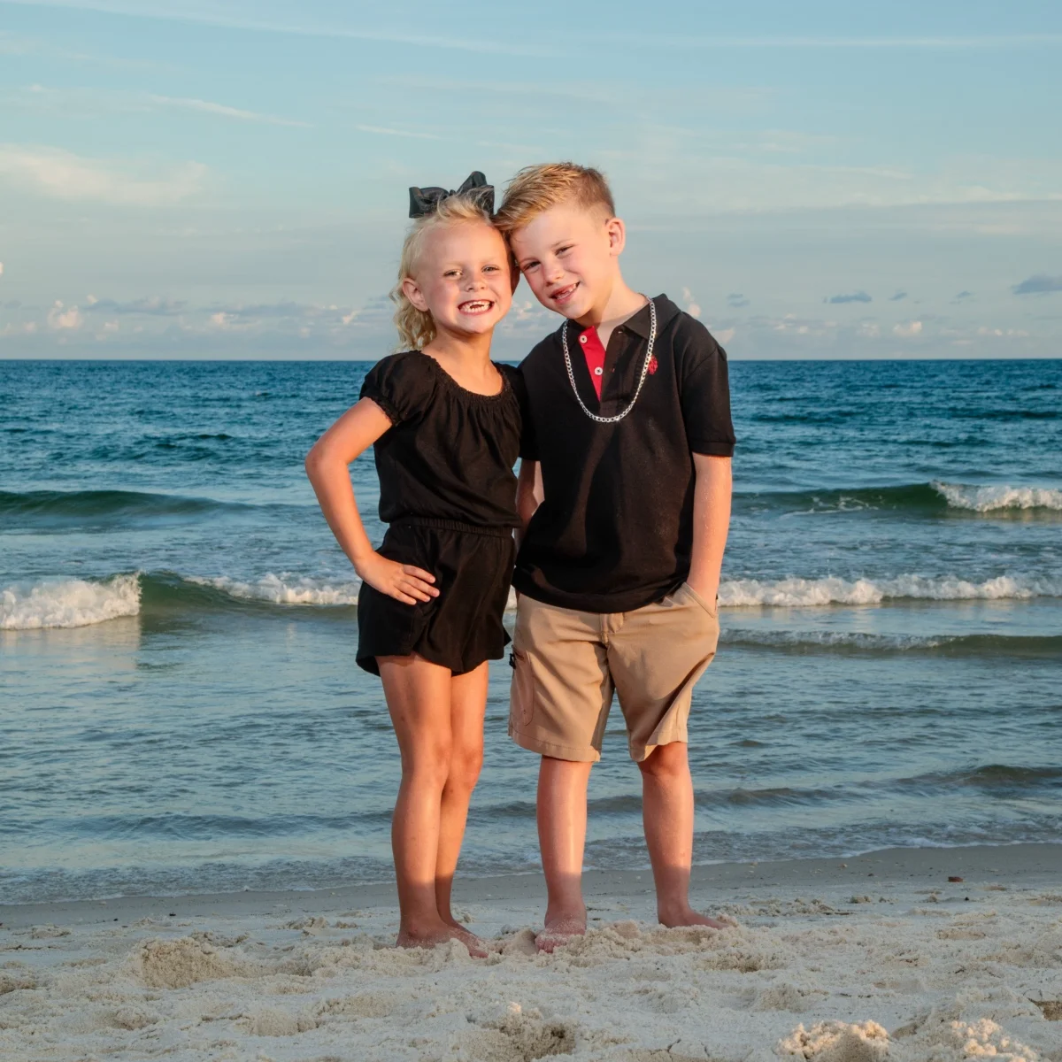 A young boy and girl standing by the water's edge during a photo session in Fort Morgan, Alabama.
