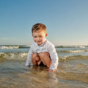 A young boy playing in the water for a photo session in Fort Morgan, Alabama.