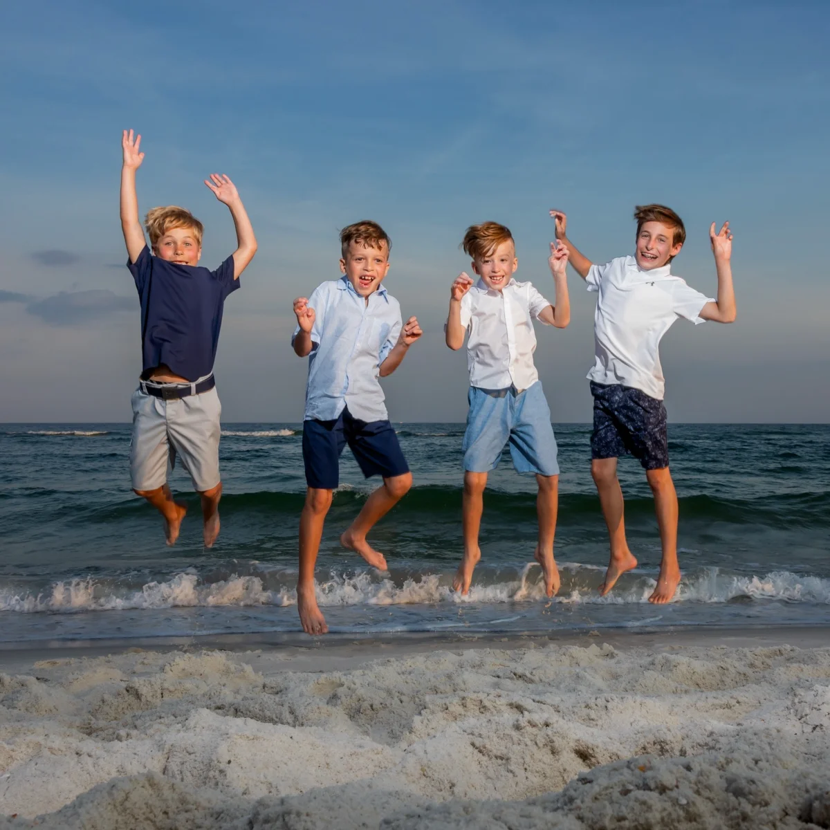 Four kids jumping in the air for a beach photo in Fort Morgan, Alabama.